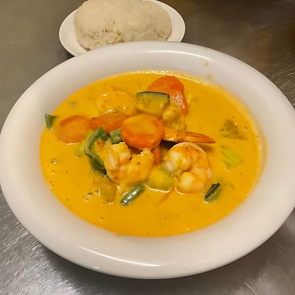 Thai yellow curry with shrimp, carrots, and green peppers, served with a side of white rice.