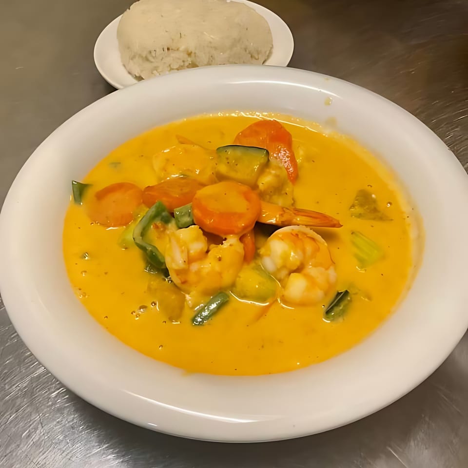 Thai yellow curry with shrimp, carrots, and green peppers, served with a side of white rice.