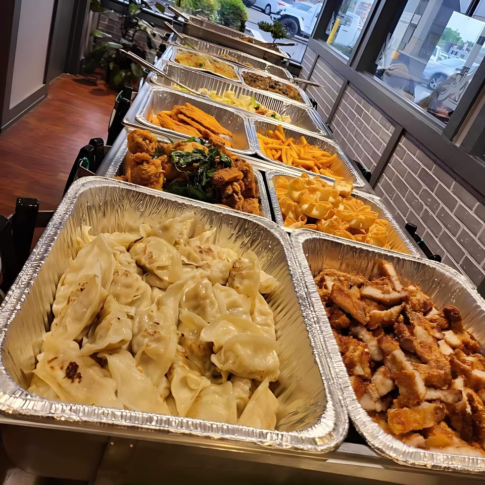 A buffet line at Thai Bistro & Bar with various Thai dishes in aluminum trays.